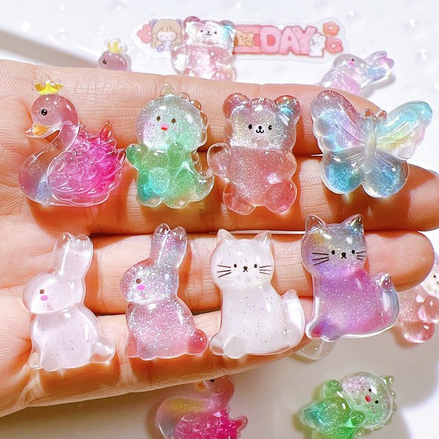 8 Stück Cartoon Schmuck-Anhänger aus Kunststoff in Multicolour mit Kaninchen, Bär, Schmetterling, Gans, Dinosaurier und Katze als Flachrückseiten-Ornament für deine Bastelprojekte - Bild 1