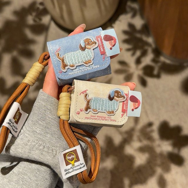 AirPods Schutzhülle mit Cartoon Dackel Stickerei und Denim Muster aus Leder inklusive Lanyard für AirPods 1, 2, 3, 4 und Pro 2 in Blau oder Beige - Bild 1