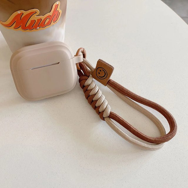 Weiche Silikonhülle mit Lächeln und Handschlaufe für Apple AirPods 4, 3, Pro 2, 1 in Braun - Bild 1
