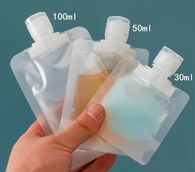 Transparente Clamshell-Standbeutel aus Kunststoff mit Ausgießer für Reiseflüssigkeiten wie Handdesinfektionsmittel, Lotion oder Shampoo - Bild 1